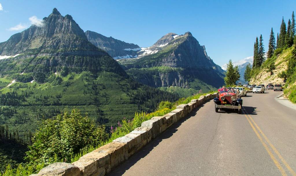 Scenic drive along Going-to-the-Sun Road in Glacier National Park with mountain peaks and turquoise lake views.
